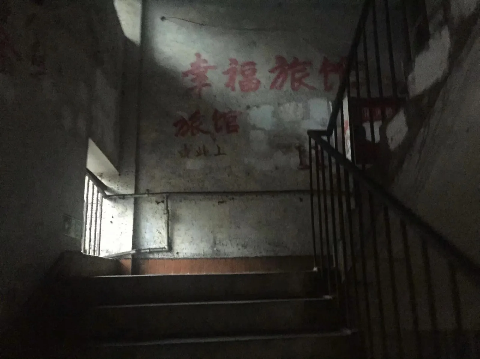 旧楼楼梯间，墙上还留着幸福旅馆的招牌，里面早已空了